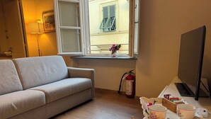 Ein Wohnzimmer mit Sofa, einem Fenster mit Blick, einem Feuerlöscher, einem Fernseher und einem Tisch mit Kerzen und Tassen.