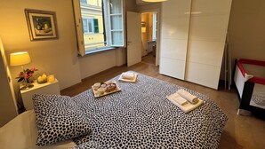 Ein Schlafzimmer mit Bett, Nachttisch, Lampe, Fenster und Kleiderschrank.