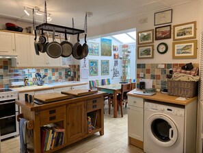 Une cuisine avec des ustensiles de cuisine suspendus, un lave-linge et un coin repas offrant une vue agréable.