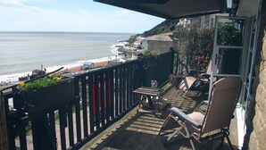 A balcony with a view of the ocean, a table, chairs, and a potted plant. - Seaside Cottage facing south overlooking Ventnor beach (Ventnor)
