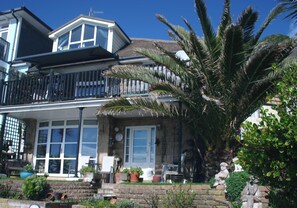 Une maison à deux étages avec un balcon, de grandes fenêtres et un palmier dans le jardin.