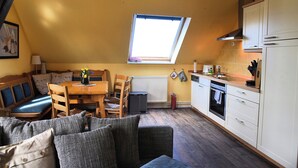 A compact kitchen with a dining area, a built-in oven, and a window. - Cozy vacation apartment on the Baltic Sea, with large garden (Behrensdorf (Ostsee))