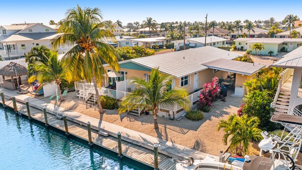 A coastal residential area with houses, a dock, and a boat. - Dog-friendly waterfront home with dock, pool, gas grill, & beach access (Key Colony Beach)
