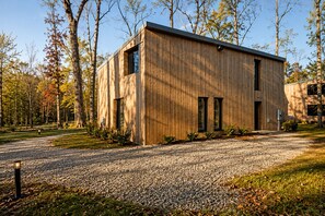 A modern wooden building with a gravel driveway and surrounding trees. - Mori House at The Retreat at Water's Edge (Tracy City)