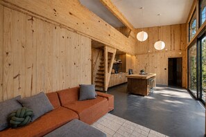 Un intérieur moderne avec un mur en bois, un canapé avec des coussins, un coin cuisine et un escalier.