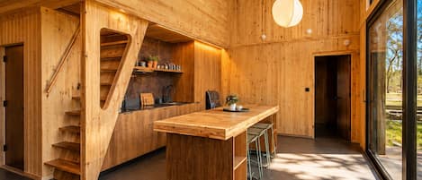 Een moderne keuken met houten wanden, een centraal eiland en een trap.