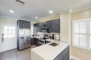 Eine moderne Küche mit Einbaukühlschrank, Mikrowelle, Backofen und Spüle.