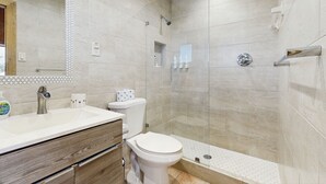 Een moderne badkamer met een douche, toilet en wastafel.