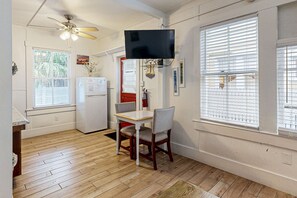 A kitchen with a dining table, chairs, a ceiling fan, a refrigerator, and a TV mounted on the wall. - Three Condos w/ Entertainment, Private Parking & Beach Nearby - Great for Groups (Key West)