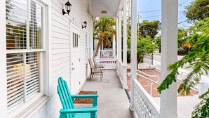 A porch with two turquoise Adirondack chairs, a white railing, and a palm tree in the background. - Three Condos w/ Entertainment, Private Parking & Beach Nearby - Great for Groups (Key West)