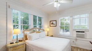 A bedroom with a large bed, two bedside tables, a ceiling fan, and large windows with blinds. - Three Condos w/ Entertainment, Private Parking & Beach Nearby - Great for Groups (Key West)