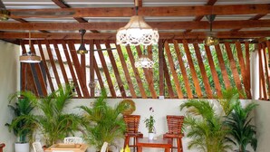 A covered outdoor seating area with wooden furniture, potted plants, and a wooden lattice wall. - The Jungle: Private Tropical Villa : Pool & 6BR (Puerto plata)