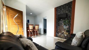 A modern living room with a black leather sofa, a wooden door, and a marble wall. - The Jungle: Private Tropical Villa : Pool & 6BR (Puerto plata)
