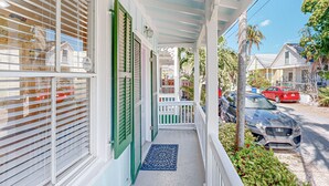 A covered porch with a blue ceiling, white railings, and green shutters. - Charming cottage with private hot tub - one block to Duvall Street (Key West)