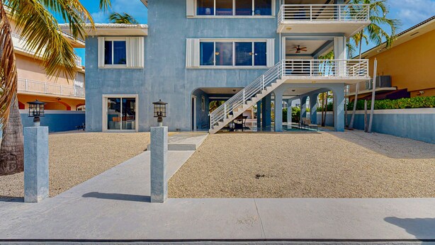 A multi-story building with a central staircase, balconies, and a covered outdoor area. - Canal-front, family-friendly home w/ soaking tub, dock access & water view (Key Largo)