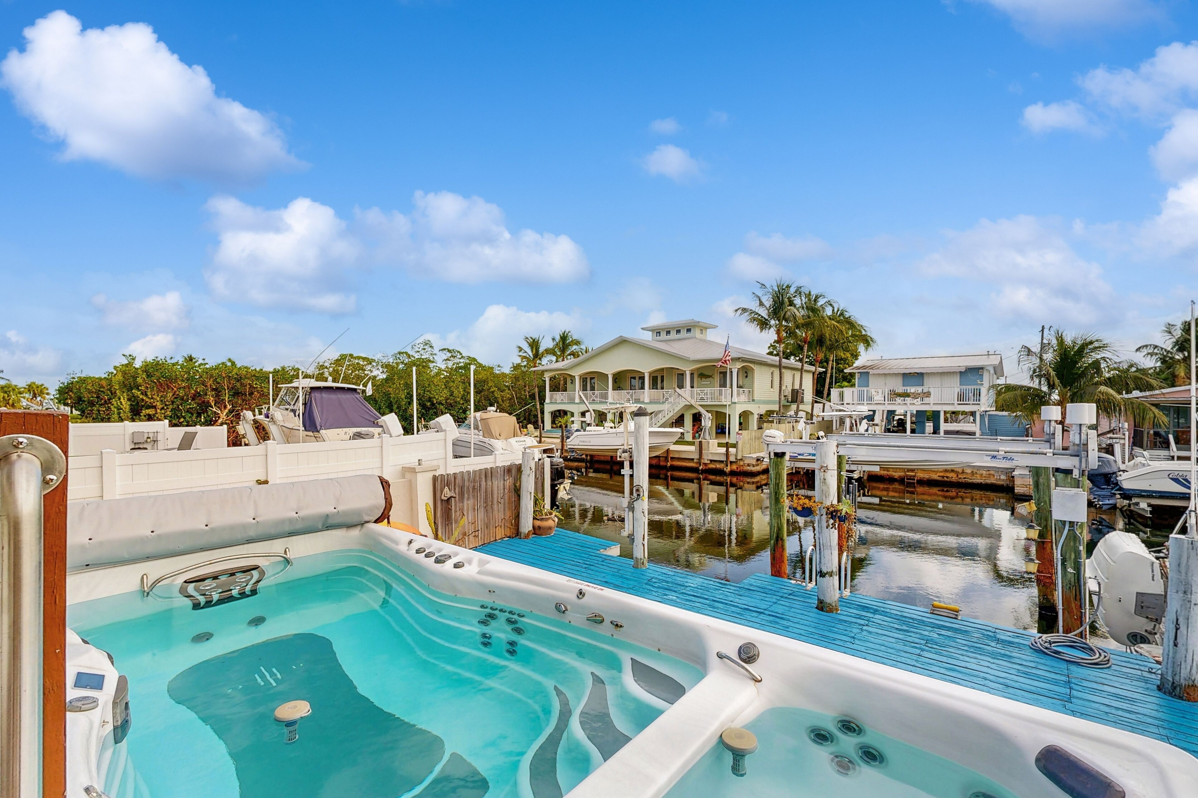 Un port de plaisance doté d’un jacuzzi, de bateaux et d’une grande maison avec balcon.