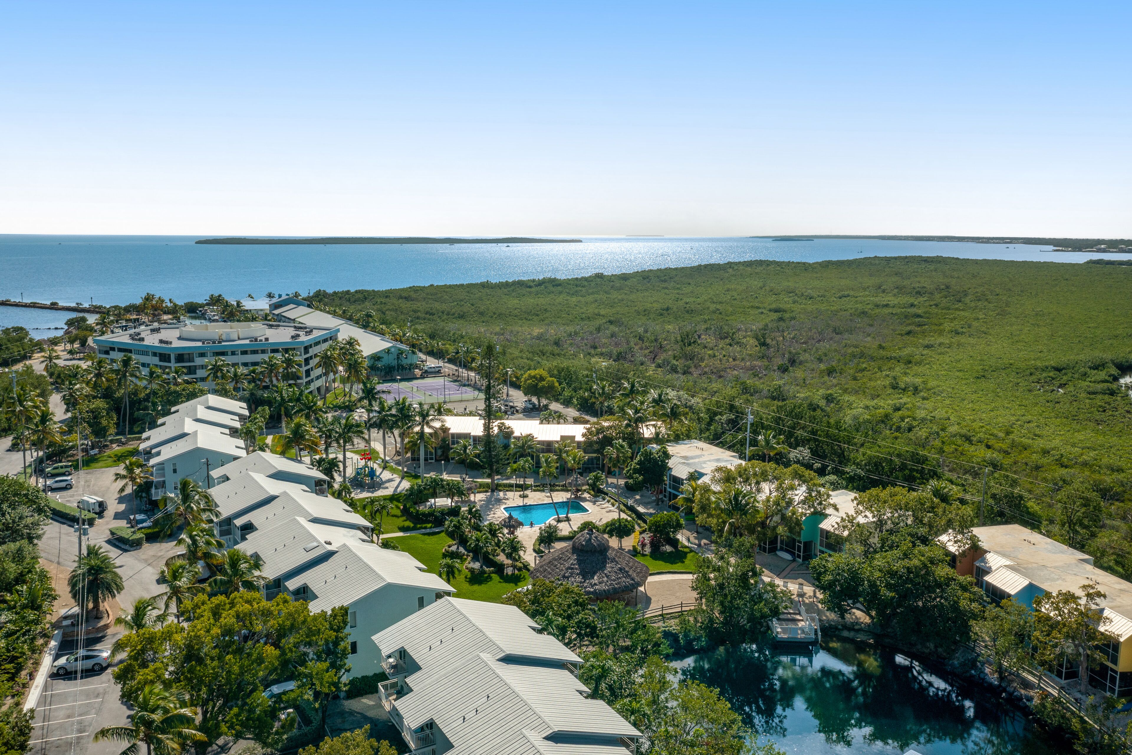 A resort with multiple buildings, a swimming pool, and a view of the ocean.