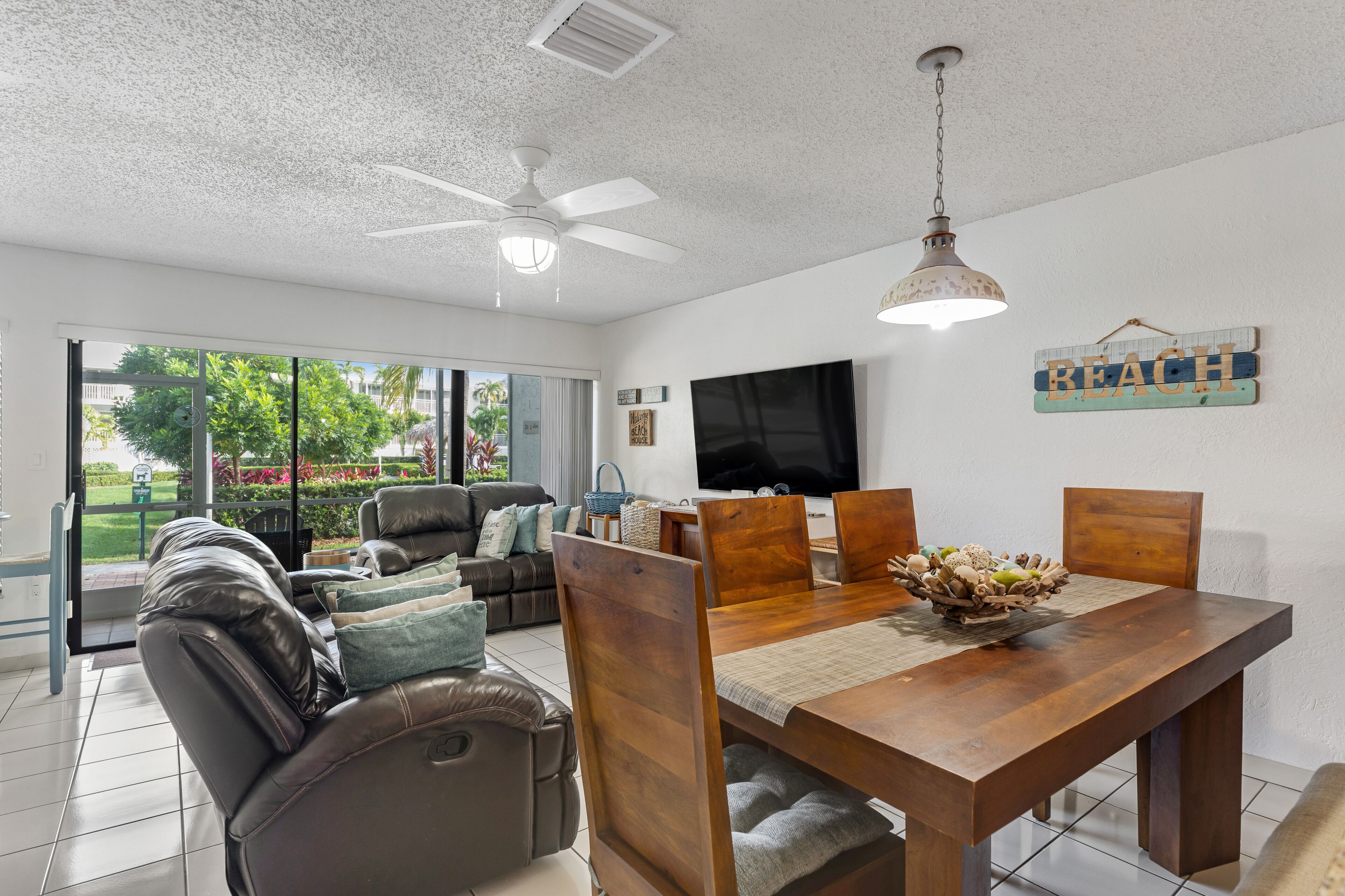 Un amplio espacio de sala con un sofá grande, una mesa de comedor y un televisor montado en la pared.