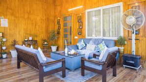 A cozy room with wooden walls, a sofa set, a fan, and potted plants. - Alaya Stays Baramasa 3 BHK Hill Retreat (Dehradun)