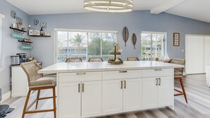 Una cocina moderna con una isla grande, armarios blancos y una lámpara colgante.