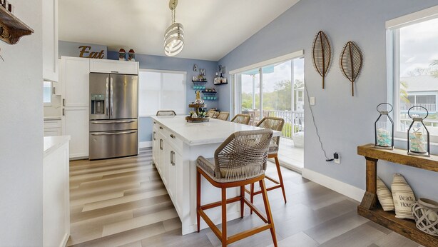 Una cocina moderna con una isla central, electrodomésticos de acero inoxidable y una lámpara de techo luminosa.