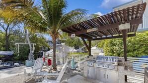 Un patio al aire libre con una parrilla, zona de estar y una pérgola.