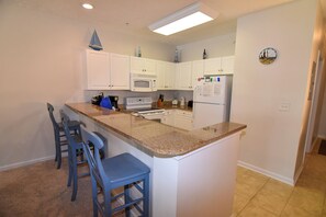 A kitchen with white cabinets, a microwave, a refrigerator, and a clock on the wall. - 3 bedroom 2 bath. Gated community. Close walk to ocean. Ocean Keyes. (North Myrtle Beach)