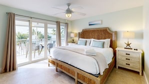 A bedroom with a bed, a ceiling fan, a nightstand, and a view of the outside. - Beach townhouse with shared pool, tennis & marina - AC, WiFi & snowbird-friendly (Key Largo)