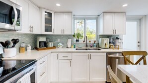 A modern kitchen with white cabinets, a built-in microwave, a coffee maker, and a dishwasher. - Beach townhouse with shared pool, tennis & marina - AC, WiFi & snowbird-friendly (Key Largo)