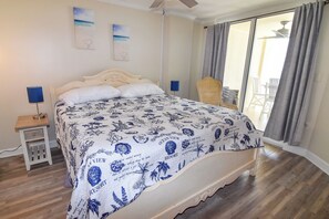 A bedroom with a bed, a nightstand, a chair, and a view of the outdoors. - OF Penthouse 3BR 2BA. Enclosed pool. Crescent Beach. (North Myrtle Beach)