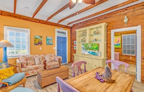A cozy room with a wooden ceiling, a sofa, a table, and a window with blinds. - Charming dog-friendly home with guest cottage & private pool - great location (Key West)