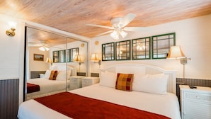 A hotel room with a large bed, a ceiling fan, a mirror, and a nightstand with a lamp. - Spacious Key West Conch Cottage with WiFi & Private Hot Tub - Dogs OK (Key West)