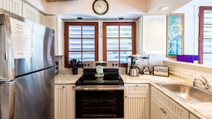 A kitchen with a stainless steel refrigerator, a black stove, and a sink. There is a clock on the wall and a window with blinds. - Spacious Key West Conch Cottage with WiFi & Private Hot Tub - Dogs OK (Key West)