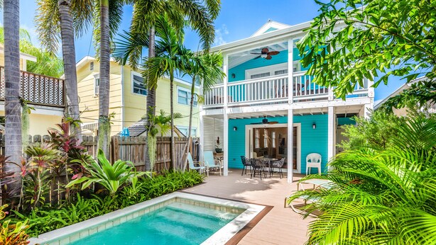 A two-story house with a pool, surrounded by tropical plants and a wooden deck. - Ground-level getaway with free WiFi, private deck, & shared outdoor pool (Key West)