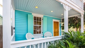 A turquoise house with a porch, white railings, and two wicker chairs. - Ground-level getaway with free WiFi, private deck, & shared outdoor pool (Key West)