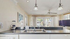 A kitchen with a double sink, a blender, a coffee maker, and a television. - Ground-level getaway with free WiFi, private deck, & shared outdoor pool (Key West)