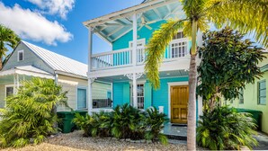 A two-story house with a balcony, surrounded by tropical plants. - Ground-level getaway with free WiFi, private deck, & shared outdoor pool (Key West)
