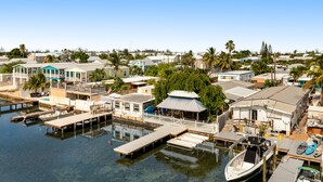 Un puerto deportivo con barcos amarrados, una casa con muelle y una vista despejada del agua.