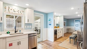 Una cocina moderna con armarios blancos, un refrigerador de acero inoxidable y una mesa de comedor de madera.
