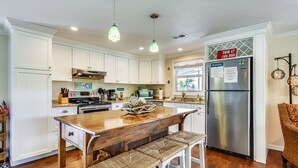 Una cocina con armarios blancos, una isla de madera y un refrigerador de acero inoxidable.