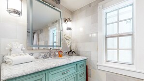 A bathroom with a marble countertop, a large mirror, a sink, and a window. - Charming, updated home near Duval St. with enclosed patio & walkable location (Key West)