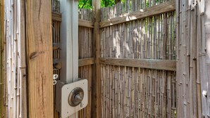 A bamboo fence with a metal gate and a security camera mounted on a post.