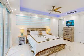 A bedroom with a bed, nightstands, a ceiling fan, a painting, and a wardrobe. - Sprawling waterfront home with pool, outdoor kitchen, game table, grill, & W/D (Key Largo)