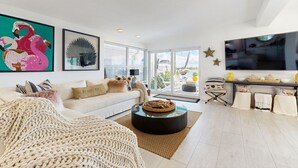 Een moderne woonkamer met een witte bank, een ronde salontafel en een grote flatscreen-televisie.