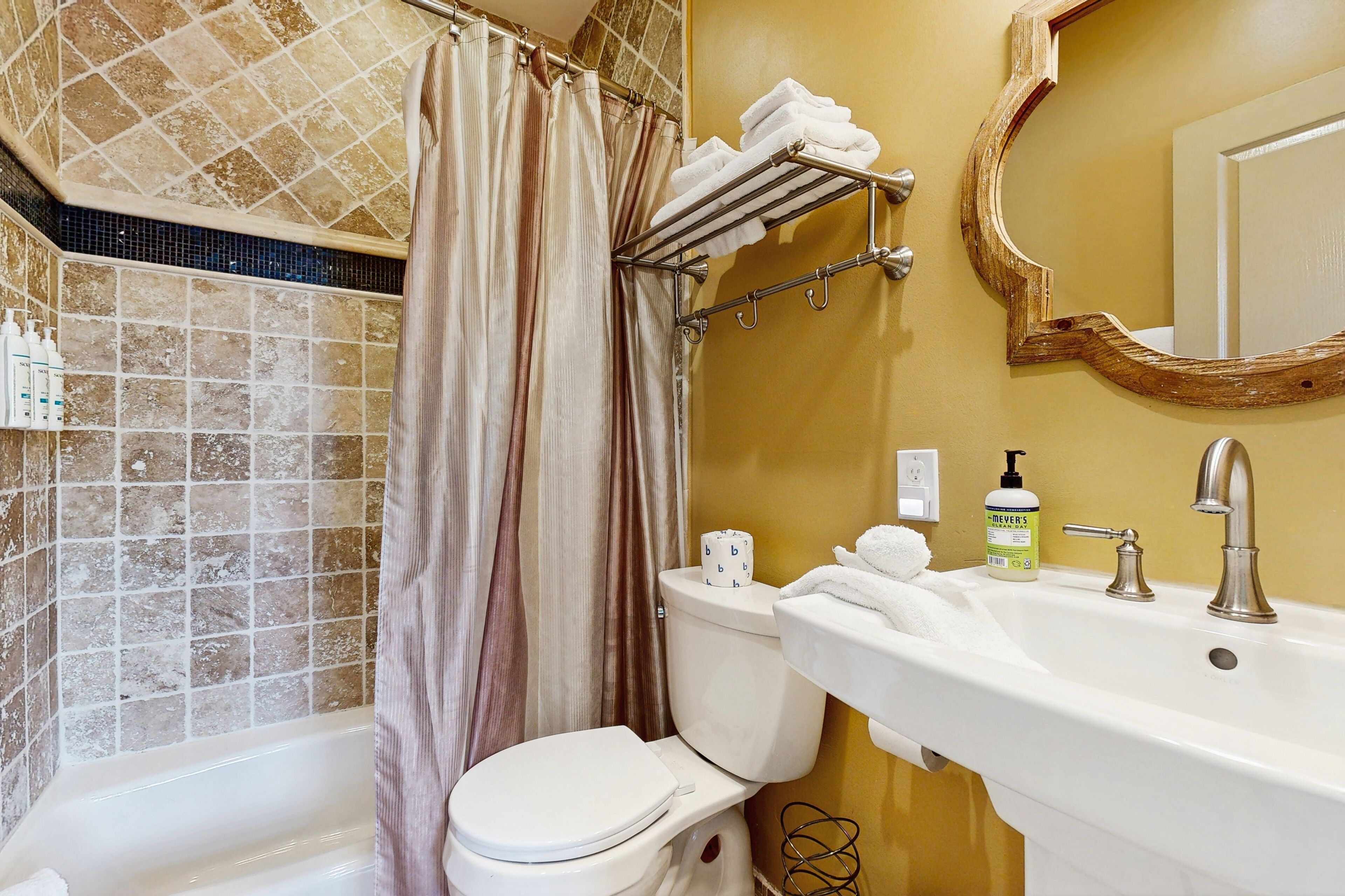 A bathroom with a bathtub, toilet, sink, and a mirror.