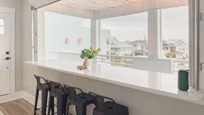 Una cucina moderna con una grande finestra, un piano di lavoro bianco e sgabelli da bar.