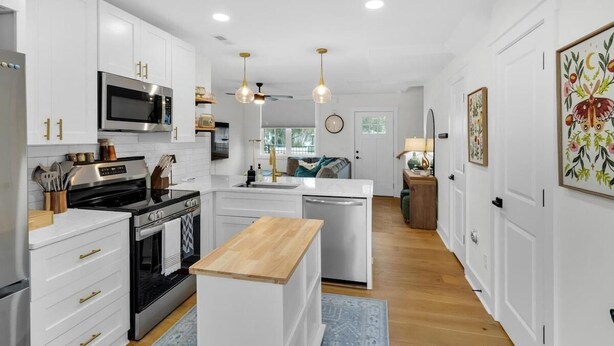 A modern kitchen with white cabinetry, stainless steel appliances, and a central island.