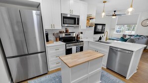 A modern kitchen with stainless steel appliances, white cabinetry, and a central island.