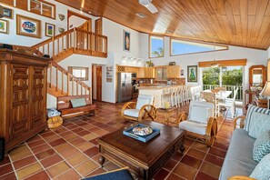 A spacious living area with a wooden staircase, a kitchen with a large island, and a dining area with outdoor seating. - Oceanfront home with a pool, dock, grill, scenic balconies, games, W/D, & AC (Tavernier)