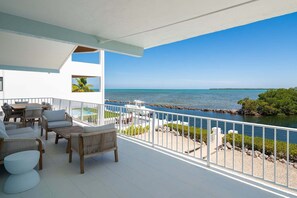 A balcony with outdoor furniture, a pool, and a view of the sea and a small island. - Oceanfront home with a pool, dock, grill, scenic balconies, games, W/D, & AC (Tavernier)
